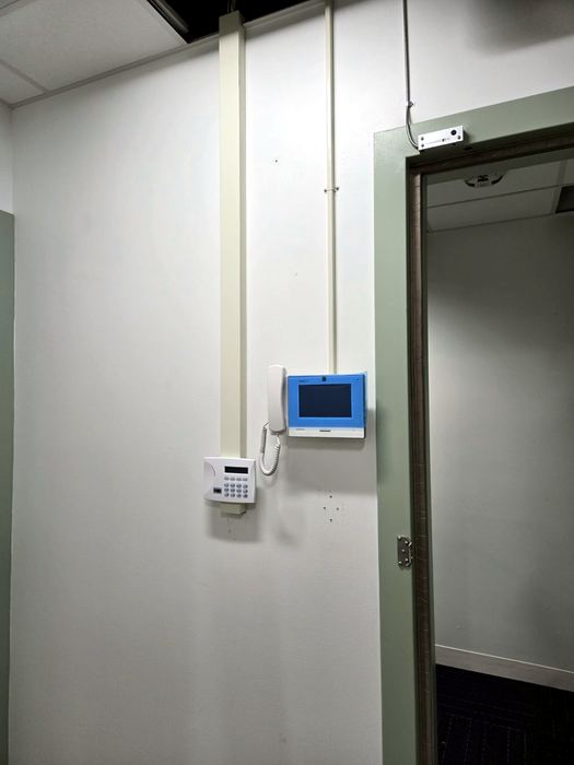 Entry panel and credential reader installed at a doorway, device face redacted
