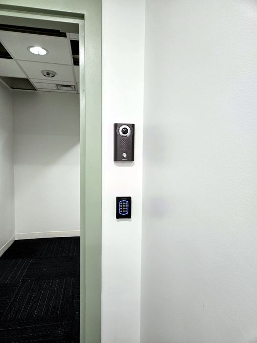 Intercom and credential reader installed on an interior wall, device faces redacted