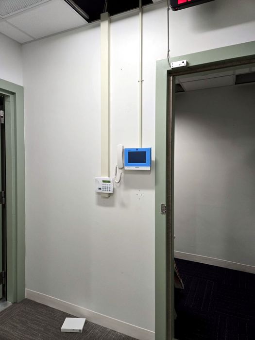 Intercom and entry panel integrated at a secure door, device face redacted